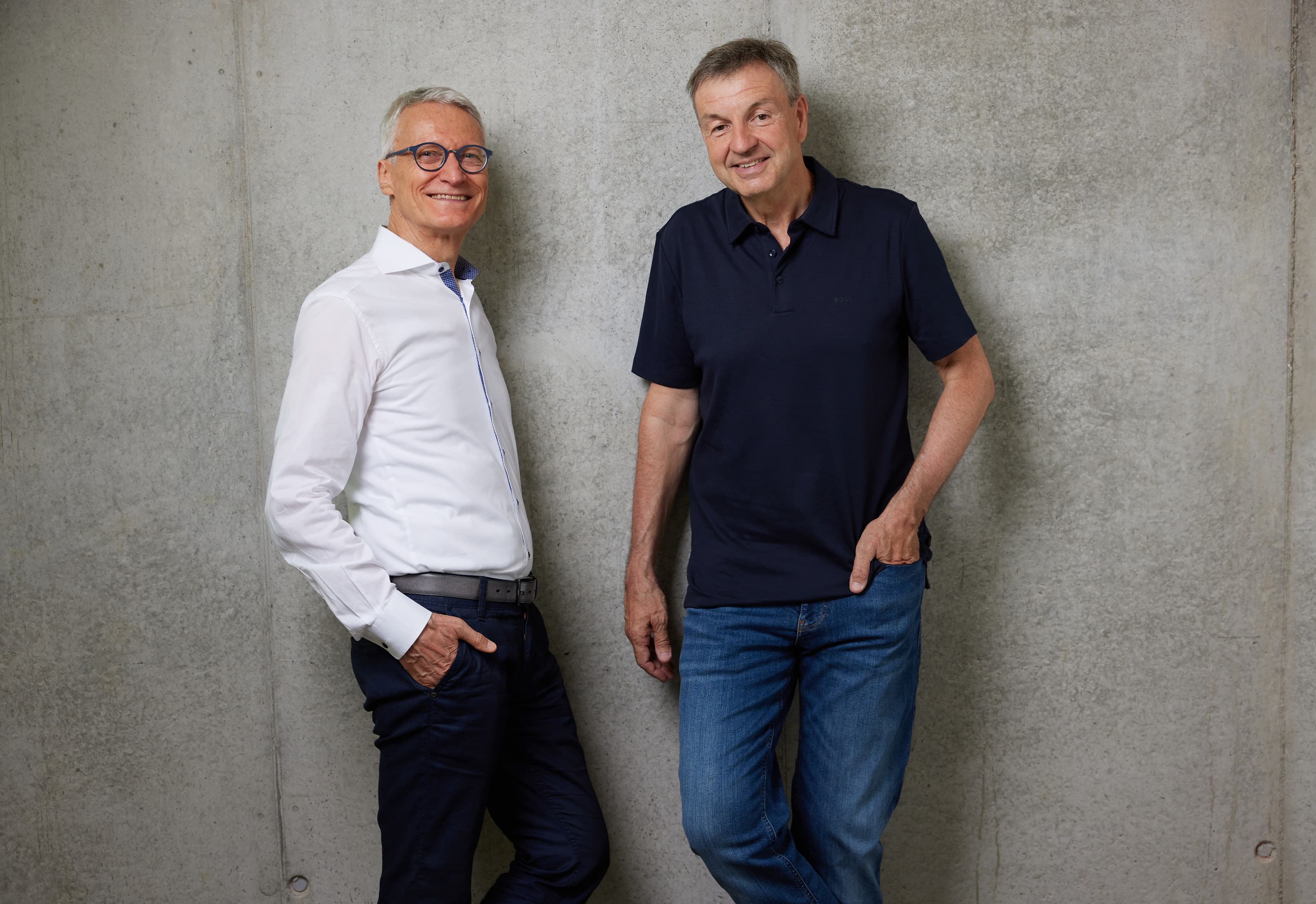 Michael Kopf (links) und Michael Basler nebeneinander vor einer Sichtbetonwand